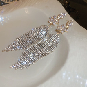 Macro shot of gold flower earrings with sparkling rhinestone tassels in a stylish tray
