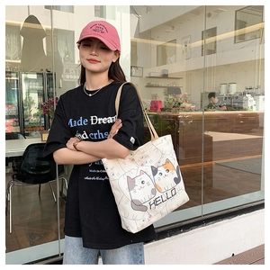 Detail of canvas tote bag featuring cute cartoon cat prints and Hello text on shoulder