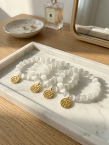Detailed macro view of white cat eye bead bracelet with golden Fu character charm