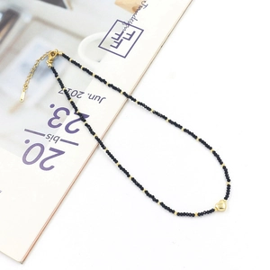 Detailed close-up of a colorful beaded necklace featuring black crystals and a golden heart