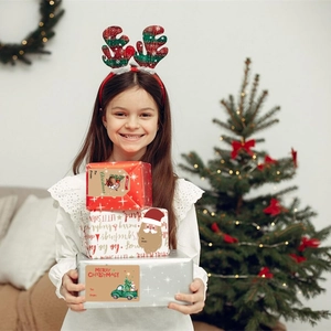 Child holding Christmas gift boxes with Merry Christmas To/From decorative labels