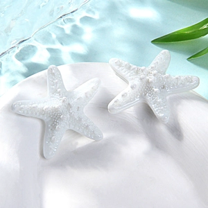 Close-up of small white resin starfish accessories on a dish with a blue water background