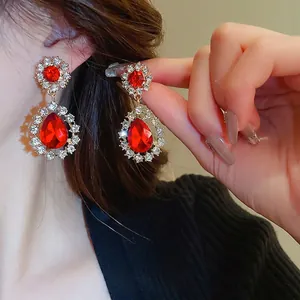 Boucles d'oreilles vintage dorées avec goutte de cristal rouge et zircon fleuri sur modèle