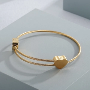 Detail of gold double-strand rope bracelet featuring a polished 3D heart-shaped charm