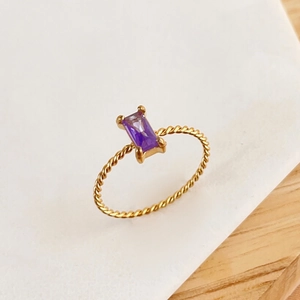 Detail of twisted gold ring band featuring a rectangular purple gemstone setting