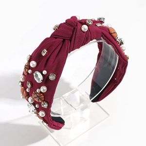 Close-up of retro dark red knotted headband with pearls, rhinestones and basketball charms