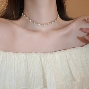 Elegant gold wavy choker necklace with imitation pearls on a female model