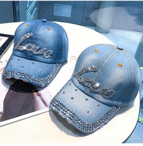 Detail der Love-Strass-Schrift und funkelnden Kristalle am Denim-Baseballcap-Rand
