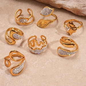 Detailed set of seven gold plated geometric rings with pavé crystals on stone background