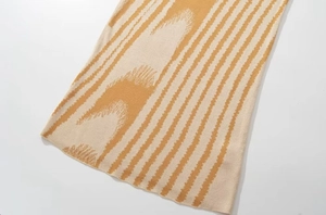 Dettaglio della trama in maglia astratta color zenzero e crema del vestito