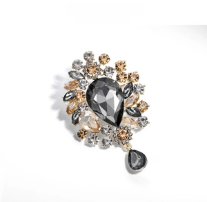 Macro detail of luxury teardrop crystal brooch with grey stones and golden alloy base