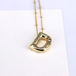Detail of 18k gold bubble letter D pendant with sparkling zircon stones and bead chain