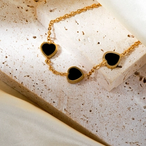 Elegant gold-plated stainless steel bracelet featuring three black enamel heart charms