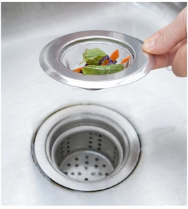 Kitchen sink strainer lifting food scraps from the drain to prevent clogging