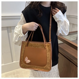 Détail du sac cabas en peluche avec poche en cuir PU marron et accent papillon rose