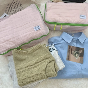 Detail of pink and green travel organizers on a soft blanket with clothing background