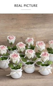 Detail of handmade crochet rose plant in white pot with a decorative ribbon bow