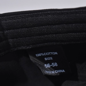 Detail view of cotton baseball cap inner tag showing 100% cotton material and 56-58cm size
