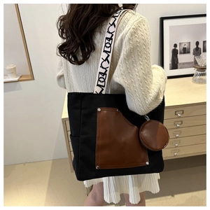 Detail of black canvas tote bag with brown leather pocket and patterned shoulder strap