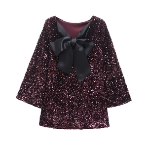 Detailed view of wine red sequins and a large black satin bow on the party dress