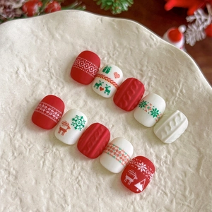 Christmas press-on nails with red and white reindeer, snowflake, and knit textures