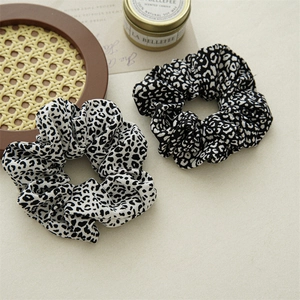 Close-up of leopard print fabric scrunchies in black and white on a lifestyle background
