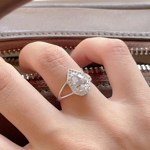 Macro detail of silver pear cut teardrop ring with pavé stones shown on a hand