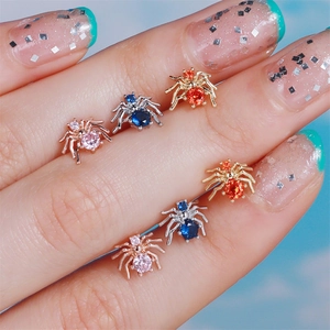 Macro view of tiny spider stud earrings with colorful cubic zirconia on finger