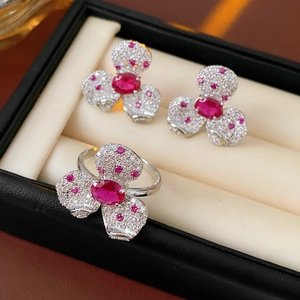 Macro view of silver clover jewelry set with red gemstones and pavé clear zircon stones