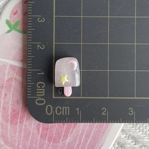 Luminous glitter resin ice cream charm with pink moon and yellow star on a scale mat