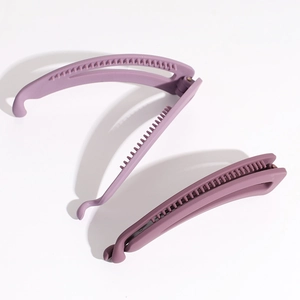 Detailed view of two minimalist matte purple banana hair clips on a white background