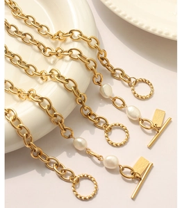 Detailed macro view of the gold OT buckle and handmade engraved tag on pearl bracelet