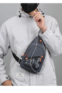 Detail of gray camo chest bag showing orange zipper puller and built-in earphone port