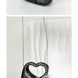 Close-up of heart-shaped marble pattern acrylic bag with rhinestones and gold chain