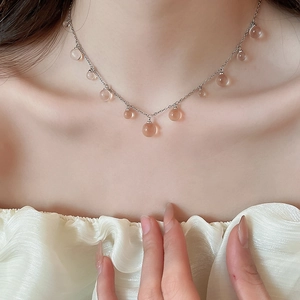 Détail du collier en acier inoxydable avec des pendentifs en perles sphériques roses