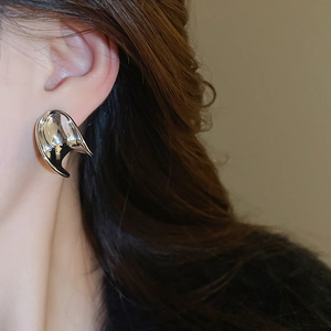 Detailed close-up of a silver liquid metal C-shaped earring on a female model