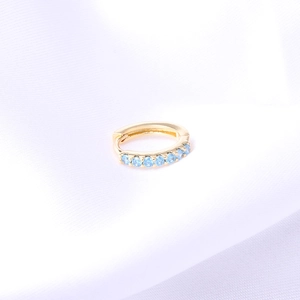 Golden huggie earring featuring vibrant sky blue gemstones in a classic hoop design