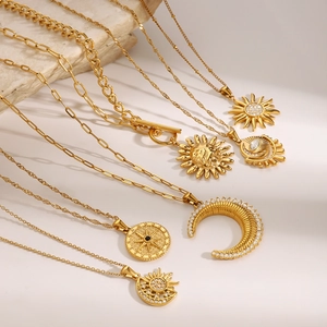 Golden stainless steel necklaces featuring sun moon and star pendants on marble