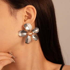 Macro detail of a large silver metallic flower earring with a pearl center on model