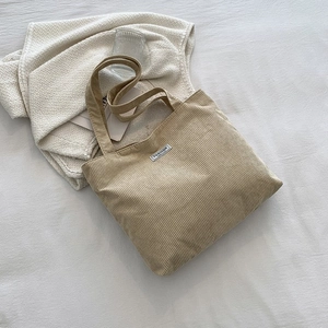Close-up of beige corduroy tote bag texture with FASHION label and vertical stripes