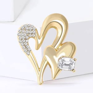 Elegant gold intertwining heart brooch with clear crystals on a white geometric stand