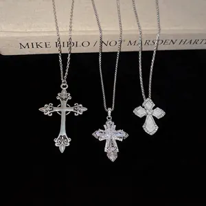 Three assorted silver cross pendant necklaces with zircon and enamel on a book