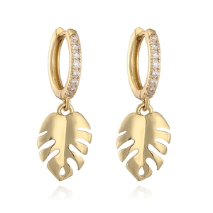 Detail of gold hoop earrings with zircon stones and monstera leaf pendants