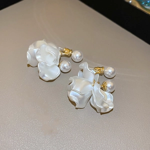 Close-up of white flower earrings with pearl pendant and golden metal components