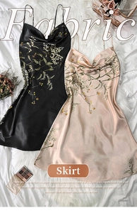 Flat lay of satin floral slip dresses in black and champagne on a plush white rug