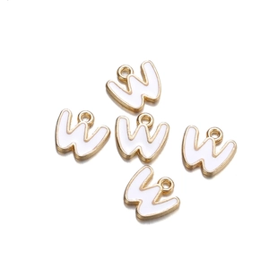 Detail of five gold-plated letter W charms with white enamel inlay for DIY jewelry