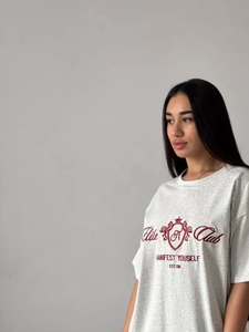 Gros plan sur la broderie rouge Elite Club du t-shirt ample gris chiné pour femme