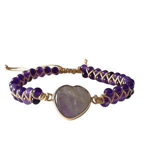 Detail of handmade purple bead bracelet with heart-shaped stone and gold-plated edges