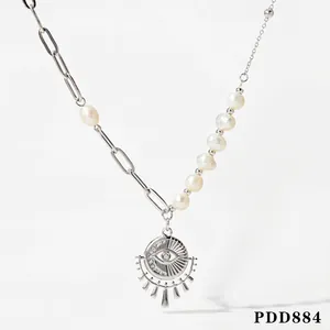 Macro view of asymmetrical pearl necklace with sun eye pendant and paperclip chain