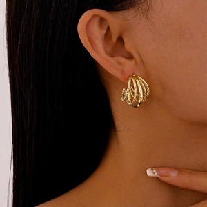 Close-up of golden multi-layer C-shaped geometric earrings with woven textured detail
